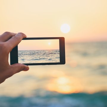 taking photo of sunset on the beach sea smartphone dslr cameras